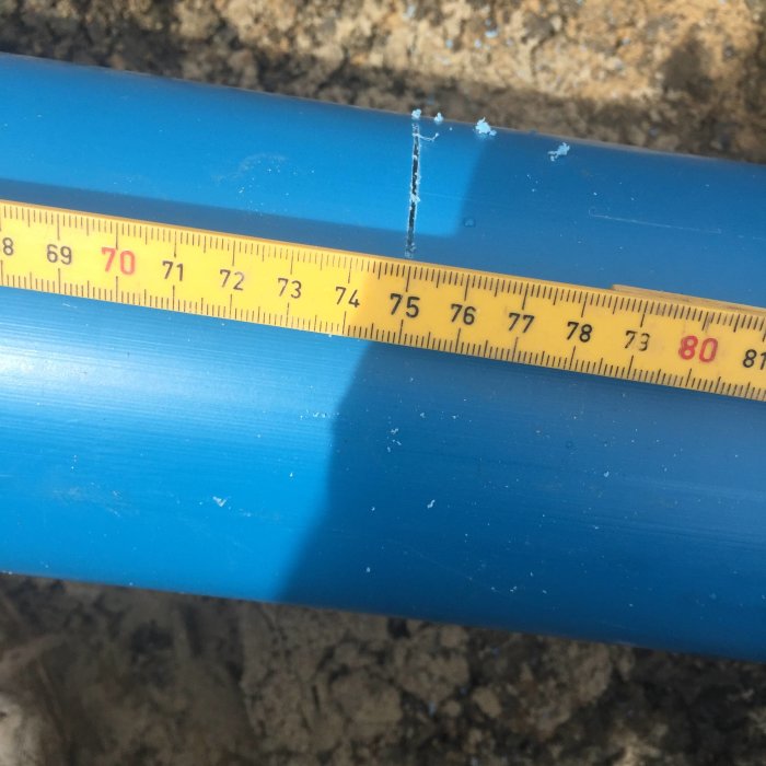 Måttband vid 75 cm markeringen på ett blått rör för visning av kapningsplats för sumprör.