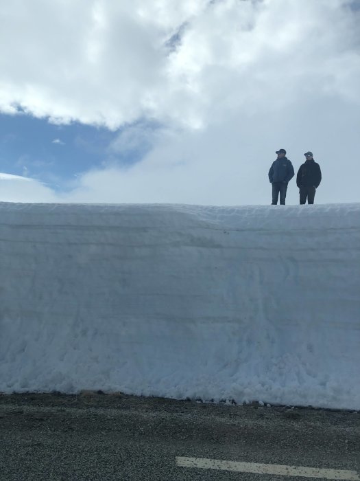 Två personer står på en snövägg vid öppnad väg i Stekenjokk.