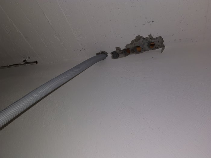 Hål borrade oregelbundet i en vit takyta med synliga ledningar och installationsrör.