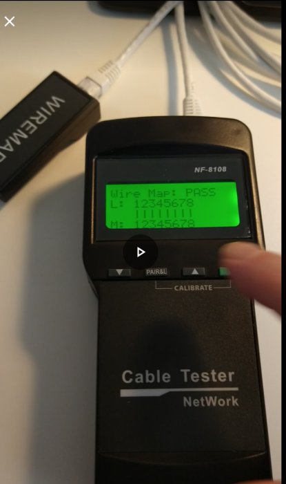 Hand håller en nätverkskabeltestare som visar godkänt testresultat på displayen.