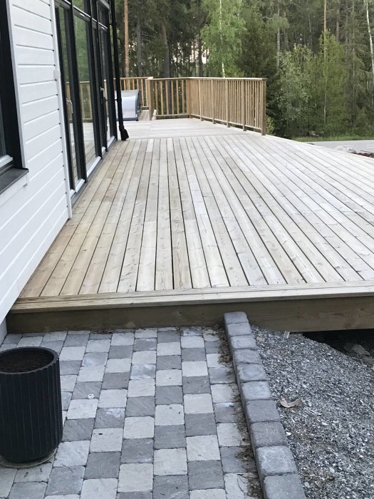 Nyligen behandlad träaltan bredvid ett hus med stengångväg och kruka.