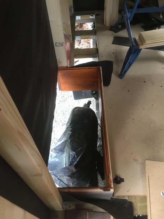 Nyinstallerat fönster i linje med yttervägg under renovering, synliga träreglar och byggmaterial.