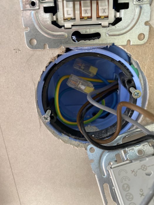 Elektrisk dosa i vägg med öppen kabeldragning och ej anslutna kablar i en byggmiljö.