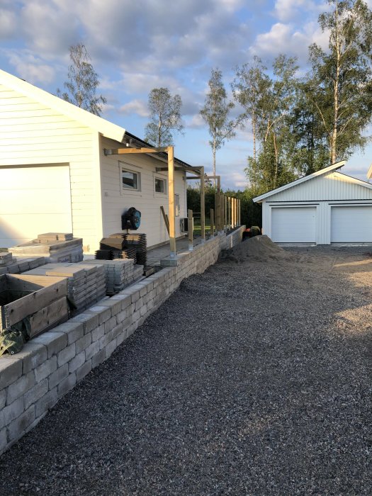 Tomtgräns med nyligen gjutna plintar och uppsatta trästolpar för ett plank, i ett bostadsområde.