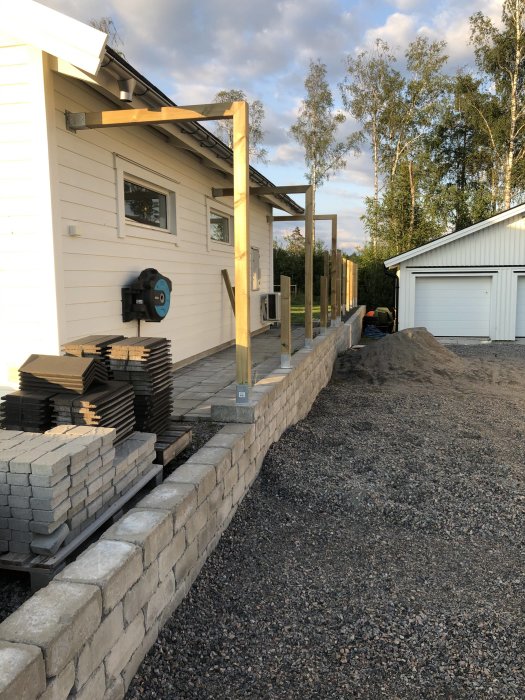 Nybyggt staket med påbörjade plintar och vertikala stolpar utanför hus.