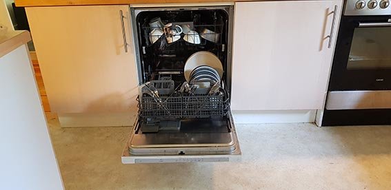 Öppen diskmaskin full med ren disk i ett kök, undrar vart torkprocessens vatten tar vägen.