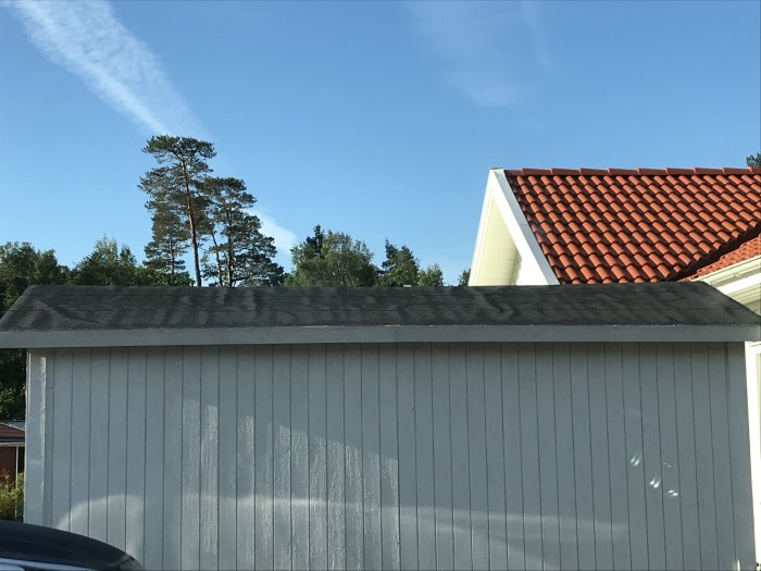 Förråd med nytt svart tak av underlagspapp och ytpapp utan synliga bubblor under dagtid.