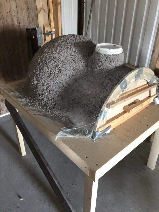 Nybyggd pizzaugn av perlite och eldfast cement formad över en pilatesboll, omålad och ännu inte härdad.