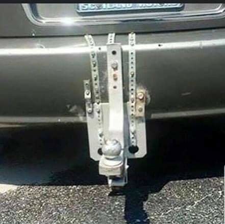 Improviserad dragkrok fäst på bilens bakdel med flera metallplattor och bultar.