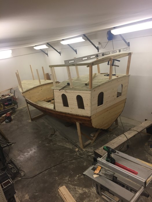 Under konstruktion av ett träbåtsprojekt i en verkstad med ett nyinstallerat räcke på övre däck.