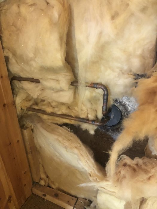 Isoleringsmaterial med rörinstallation i ett ofärdigt rum som ska bli förråd.
