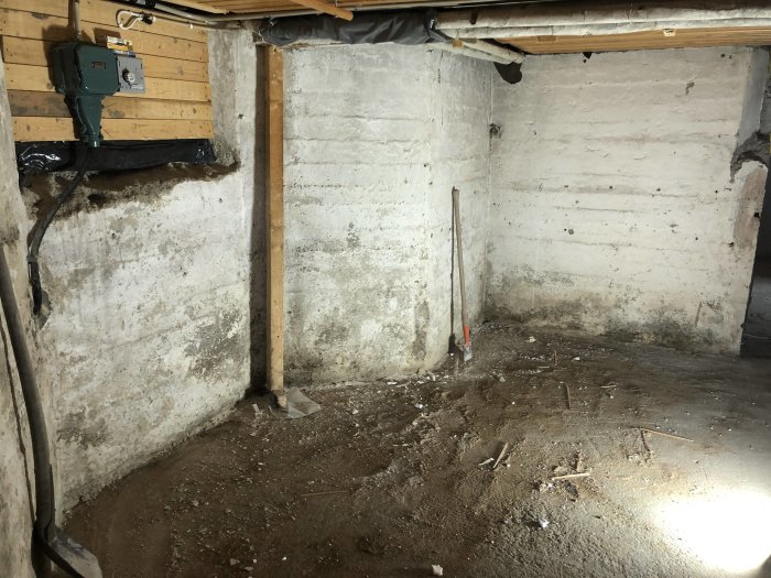 Ofärdigt förrådsrum med betongväggar, oslipat betonggolv och sparsam belysning.