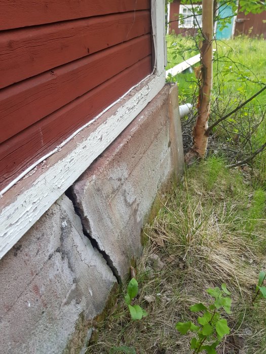 Bild på en skadad torpargrund där betongen har sprickor och husets rödmålade brädor möter den skadade grunden.