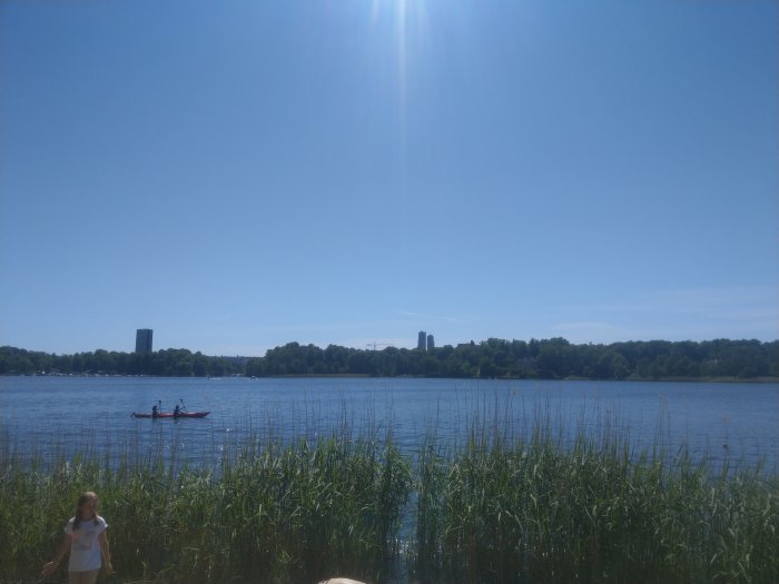 Vy över Brunnsviksbadet med höga byggnader i bakgrunden och personer som paddlar kajak.