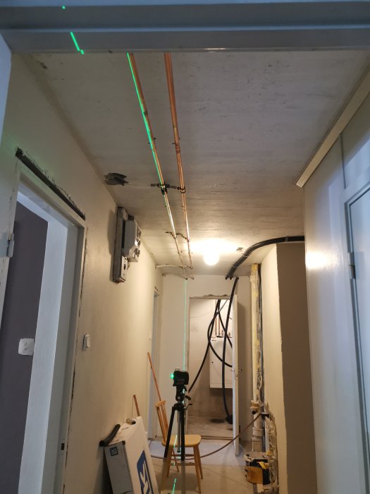 Laserinstrument projicerar gröna linjer i en pågående renovering av en korridor.