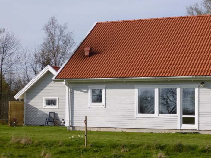 Hus och garage med Z-panel fasadbeklädnad i olika färgtoner och rött tegeltak.