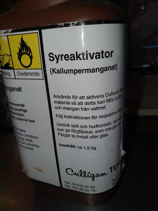 En etikett på en Culligan dunk innehållande syreaktivator kaliumpermanganat med varningsikoner.