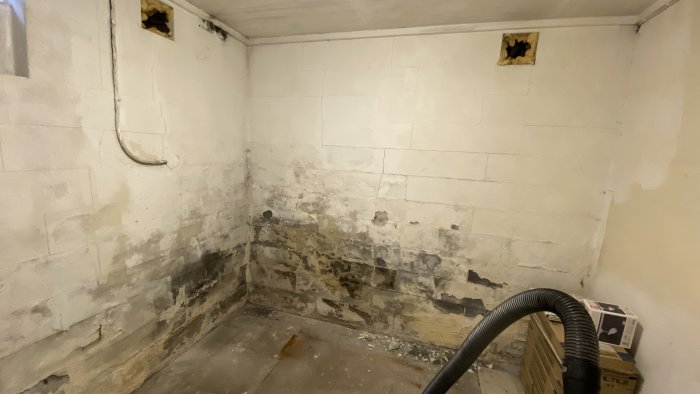 Fukt- och mögelskadad källarvägg i lättbetong med synliga sprickor och avflagning.