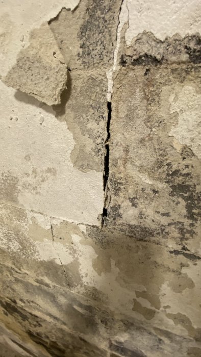 Fuktskadad lättbetongvägg med flagande färg och en synlig spricka, tecken på behov av reparation.