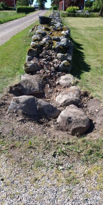 Infart med flyttade stenar och schaktad mark för att bredda öppning i stenmur.