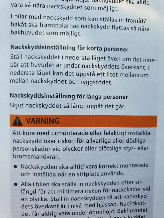 Bild på en instruktionsbok om nackskyddsinställning, varningar och tips baserat på personens längd i en bil.