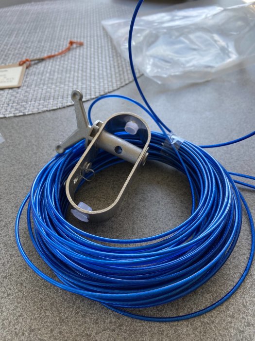 Blå kabelrulle med metallfäste och plastskydd för montering i pool, utan instruktioner.