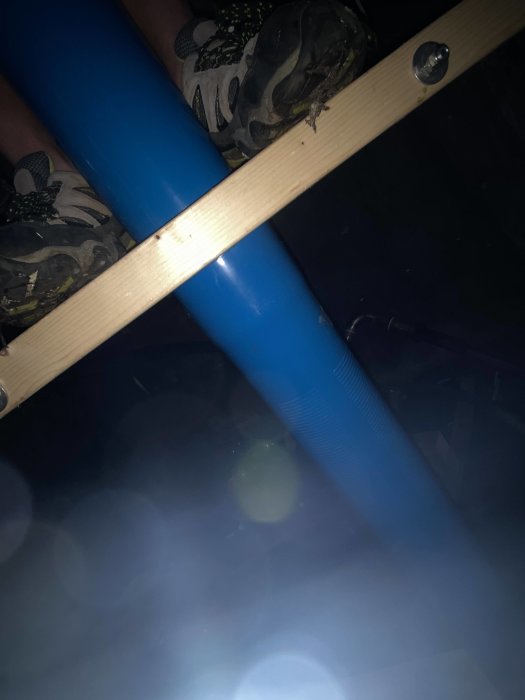 Blått filterrör och stabiliseringsplanka under brunnsborrning i dunkelt ljus.