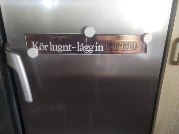 Reparerad kylskåpsdörr med skylt som säger "Kör lugnt - lägg in ETTAN".