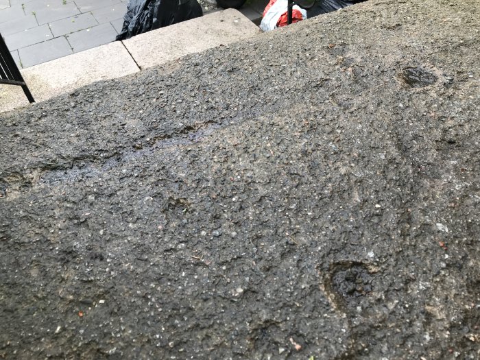 Sliten betongyta med rester av gammal epoxy som behöver diamantslipning.