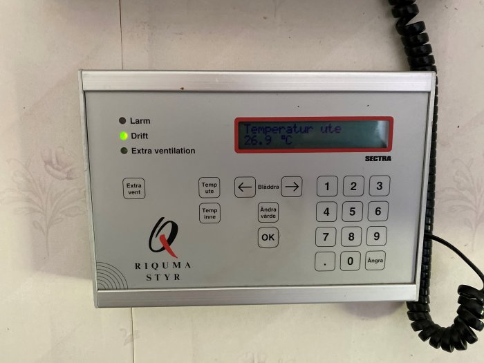 Kontrollpanel för FTX system QLV6 med temperaturvisning och knappsats, märkt 'Riquma Styr'.