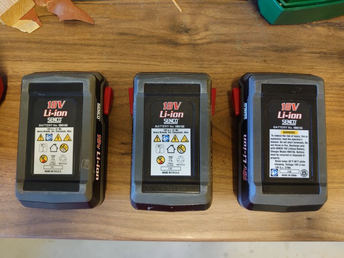 Tre liknande 18V Li-ion batterier på ett bord, det vänstra märkt med tillverkning i USA.