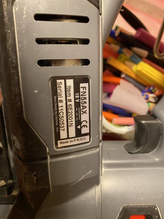 Närbild av ett slitet verktygsbatteri med etikett och tydliga slipmärken på höger sida.