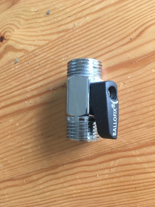Mini-kulventil med svart vred på träunderlag.
