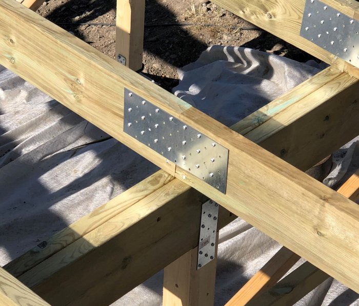 Träreglar sammanfogade med skråspikning och metallvinklar i ett byggprojekt.