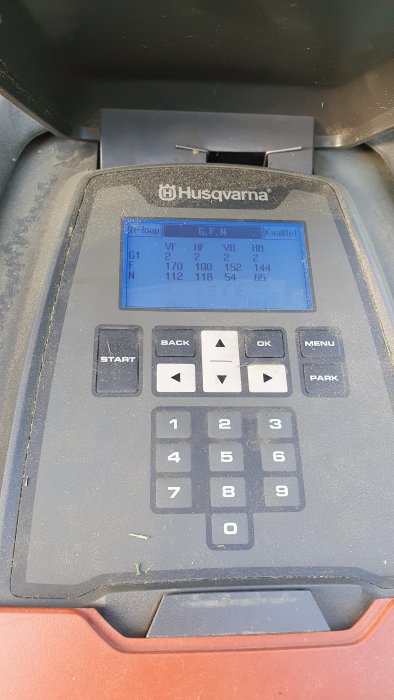 En skärm på en Husqvarna-enhet som visar olika värden, omringad av ett tangentbord med nummer och funktionstangenter.