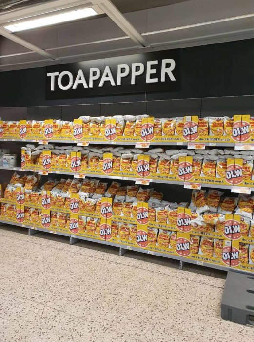 Hyllor i en butik felaktigt fyllda med chips under en skylt som säger "Toapapper".