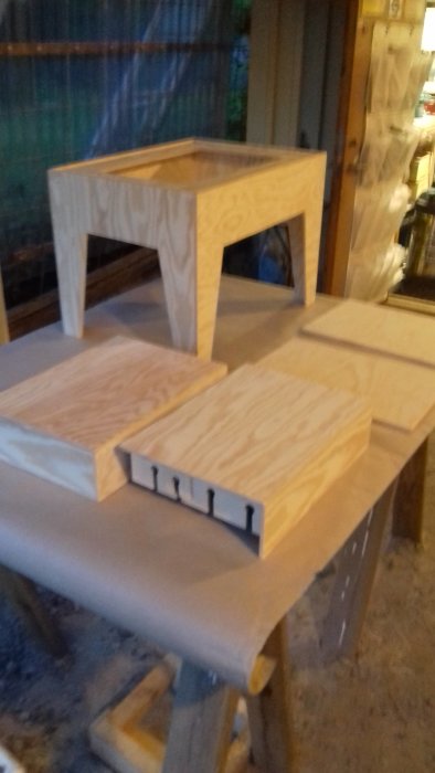 Dörrar, klaffar och benstativ i trä uppställda för betsning i en verkstad.