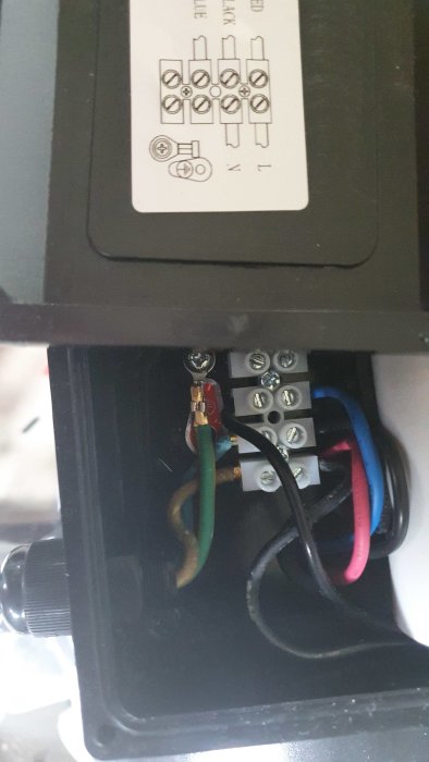 Elanslutningar inuti en poolpump med gröna, svarta och röda kablar fästa vid skruvklämmor.