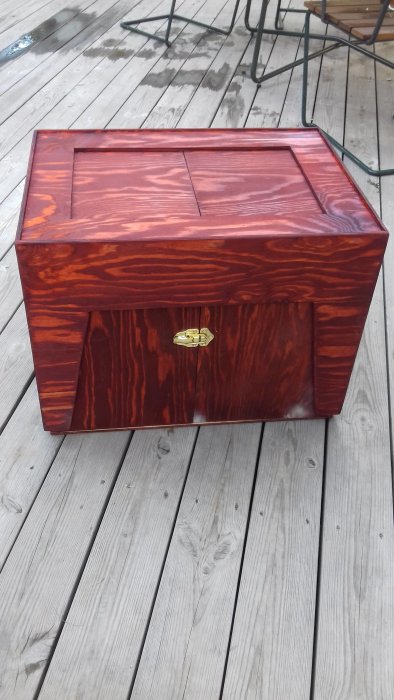 Hemmagjord trälåda med rödbrun mörk finish och mässingsbeslag på ett trädeck.