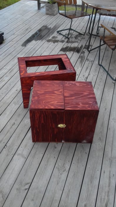 Handgjord trälåda med rödmönstrad yta och öppningsbart lock på träaltan.