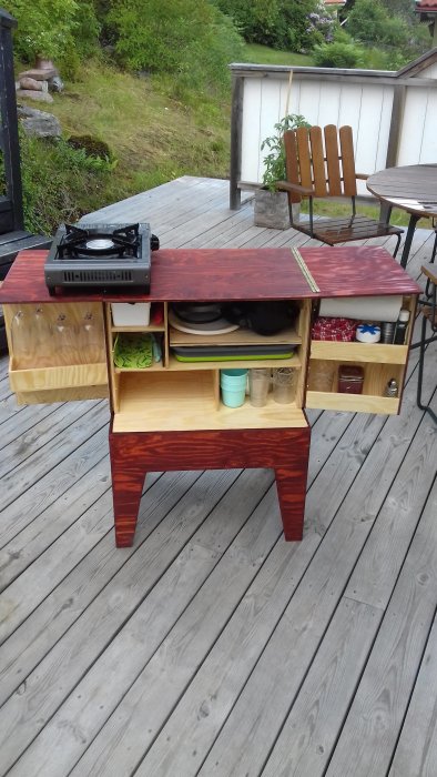 Ett handgjort utomhuskök med öppna lådor och hyllor på en träaltan.
