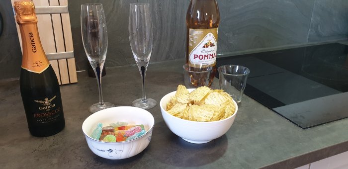 Nytt köksgolv och bänkskiva med firande Prosecco, champagneglas, skålar med chips och godis, reflekterande i det nyslipade golvet.