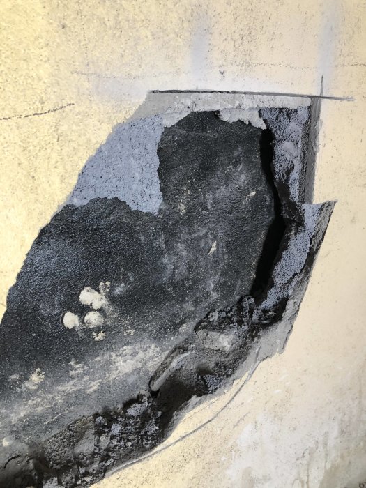 Skadad lättbetongvägg med spårning för pex-slangar i en källare