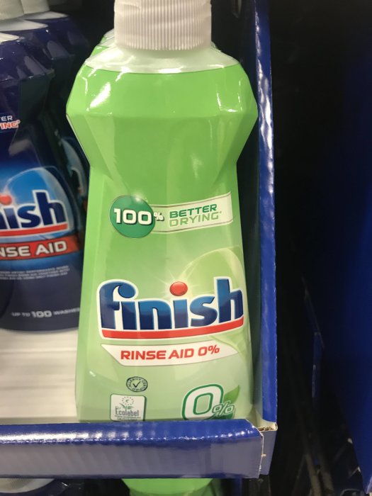 Flaska med Finish sköljmedel märkt med "100% Better Drying" och "Rinse Aid 0%" i en hylla.