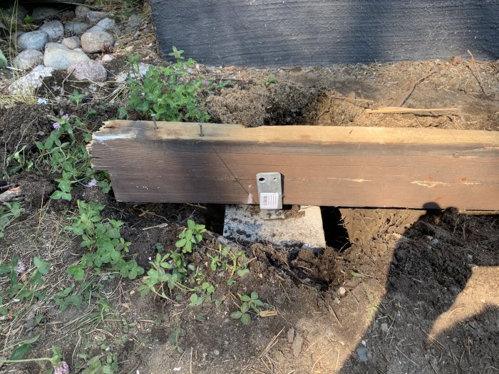 En träregel ligger på marken för att demonstrera höjden för ett byggprojekt nära en svart duk.