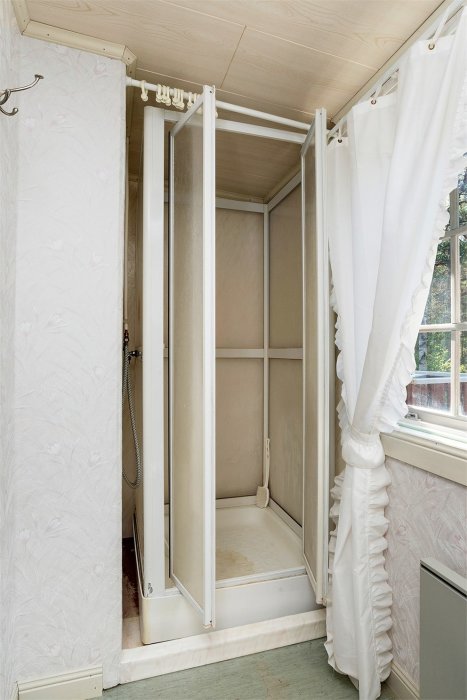 Duschhörna med mögelspår och missfärgningar i ett äldre badrum.