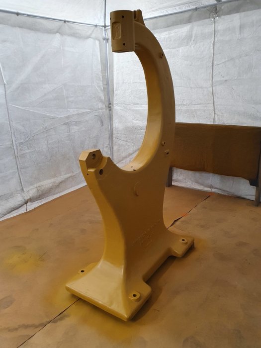 Nygjord gulfärgad epoxigrund på en demonterad bandsågsställning i ett tält.