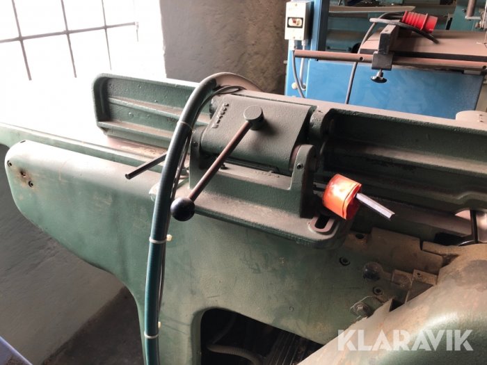 Grönt metallställdon för bearbetning av material med rattar och spakar, närbild på kontrollpanelen.