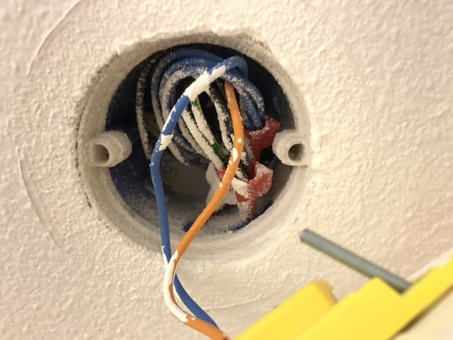 Elektriska kablar som sticker ut från en takdosa, med blå och orange kabel synlig.
