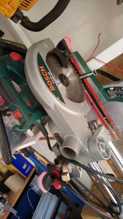 En dammig Bosch geringssåg hängande på en verktygsorganisatör, med tecken på användning och slitage.